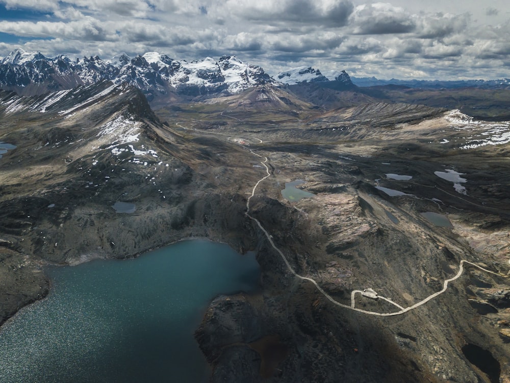 aerial photography of lake surrounded with mountains under cloudy sky