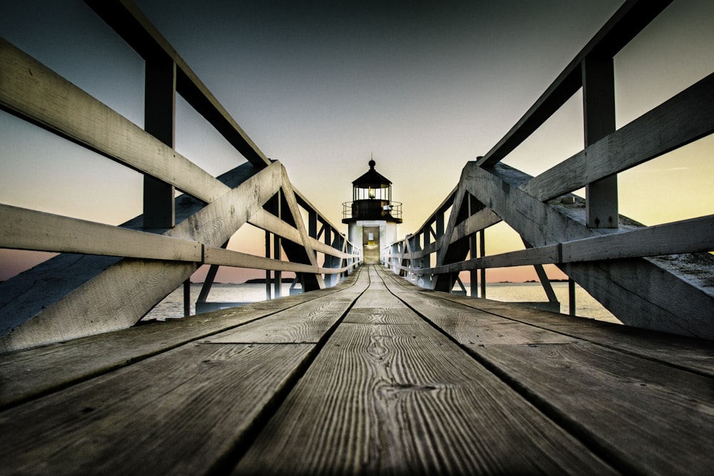 a wooden pier with a light house in the background
