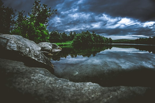 rock formation surrounded by trees and body of water in Naugatuck State Forest United States