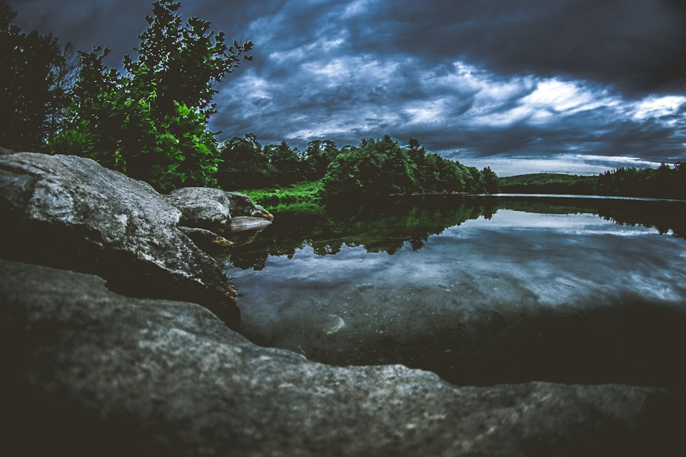 rock formation surrounded by trees and body of water