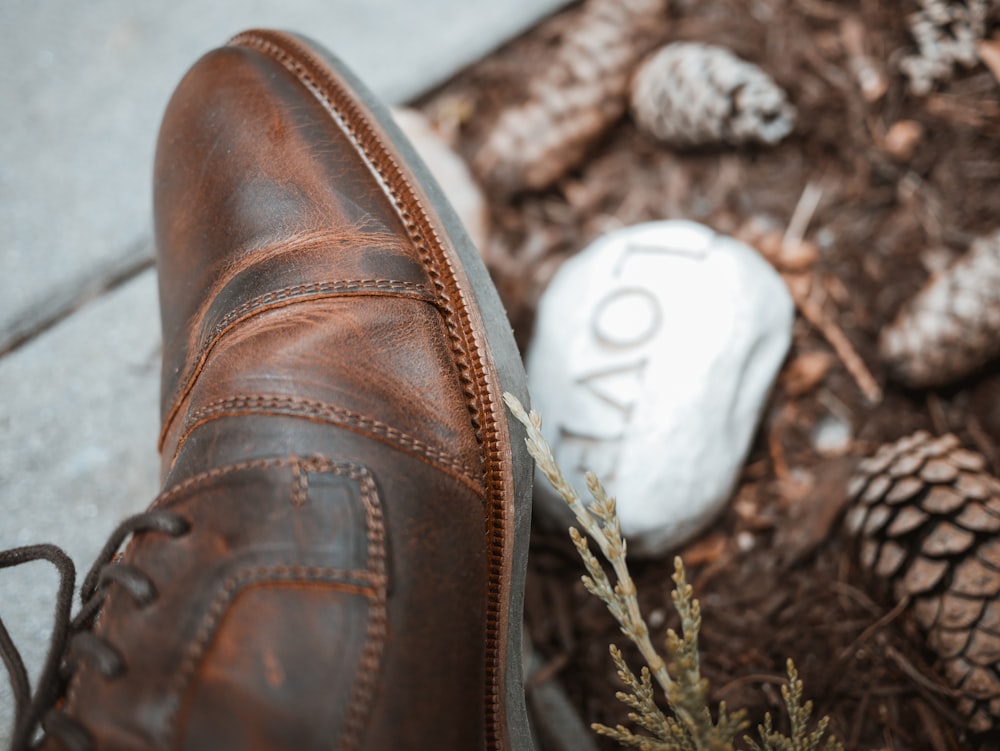 person wearing unpaired brown leather shoe