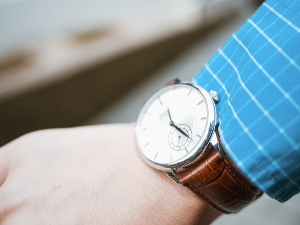 round silver-colored analog watch with brown leather strap