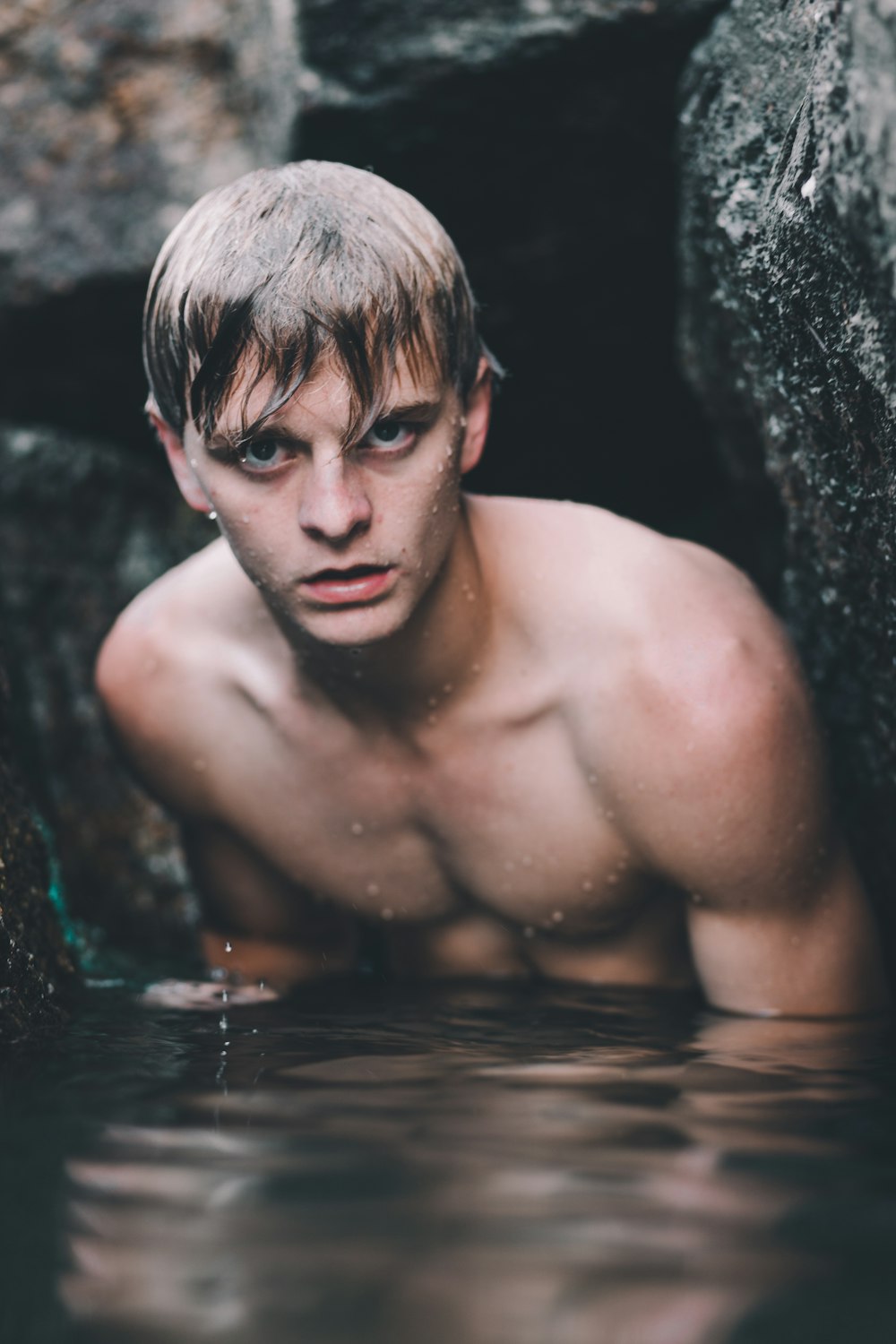 man standing between rock on body of water