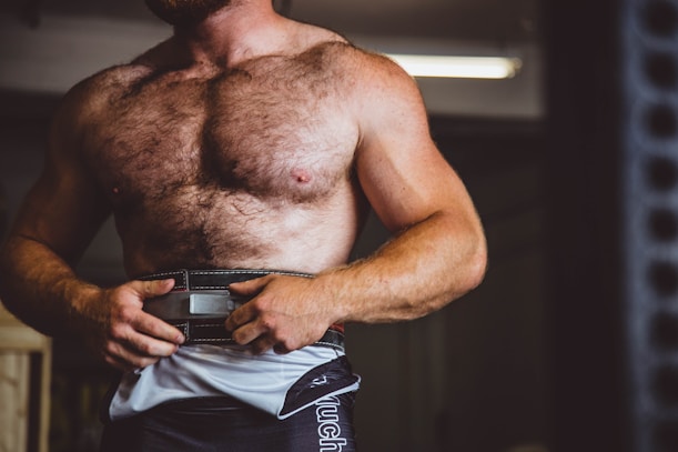 a hairy lighter skinned, shirtless man wearing a weight lifting belt