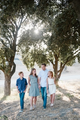 photography poses for family,how to photograph woodward park in fresno, california; family standing in front of trees