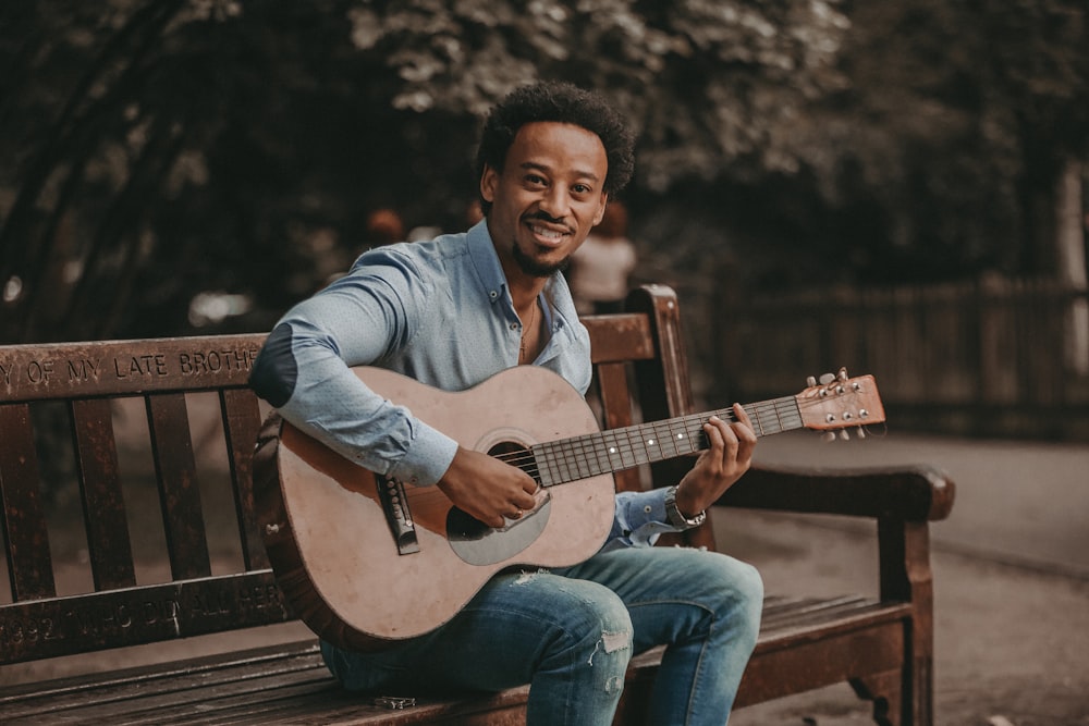 man sitting on bench playing guitar