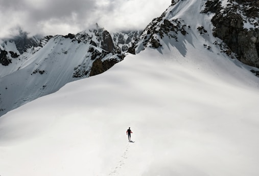 man climbing snow-covered mountain