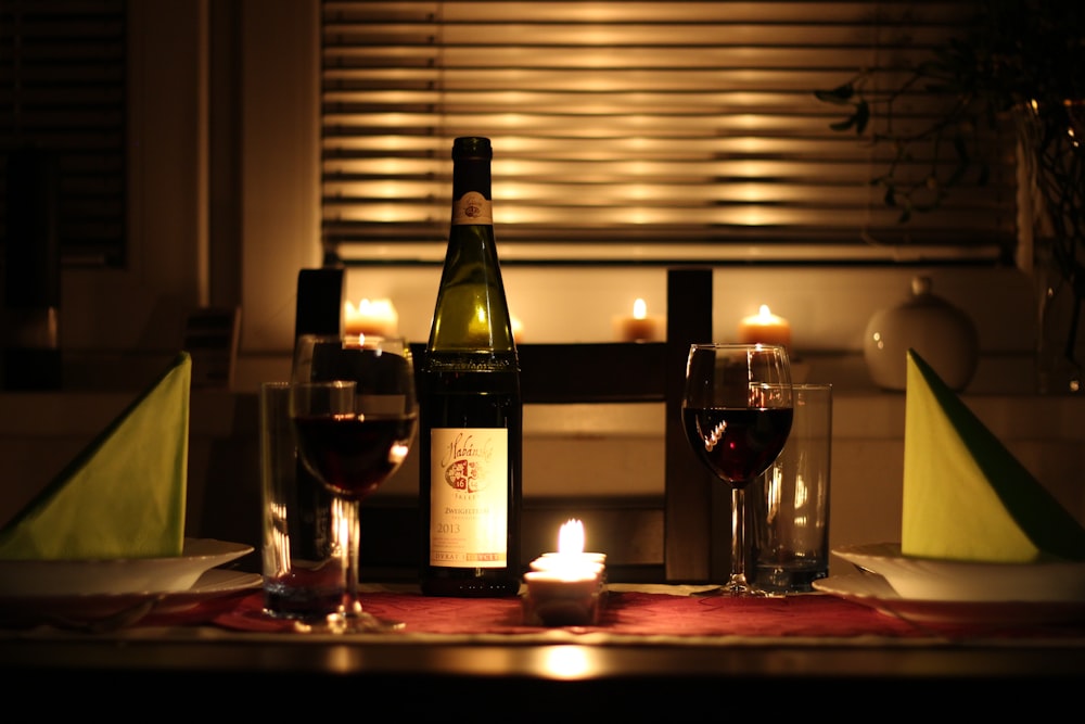 テーブルの上のボトルの横にワインで満たされたワイングラス