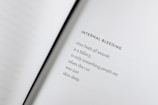 An open book with a poem titled 'Internal Bleeding' written on the right page. The text is centered and the page is mostly blank except for the poem, which discusses the concept that 'time heals all wounds' is a fallacy.