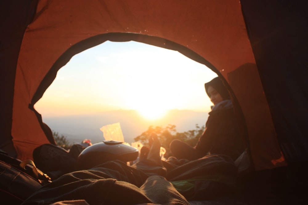 person lying inside camping tent at daytime