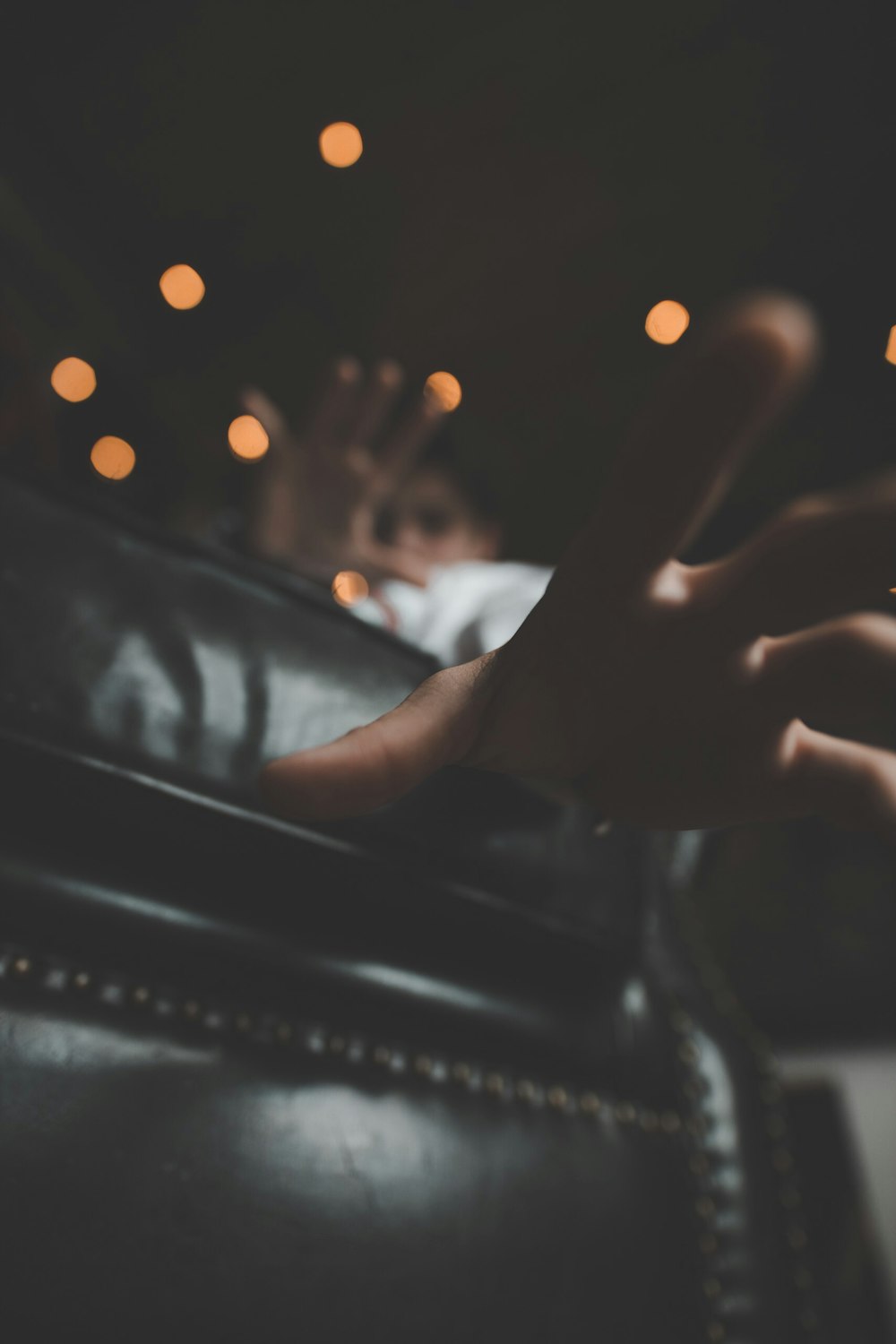 a person's hand resting on a leather couch