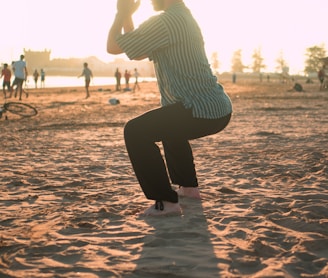 man closing his hands white squatting on sand