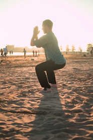 man closing his hands white squatting on sand