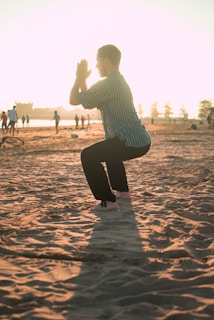 A man closing his hands white squatting on sand