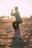 man closing his hands white squatting on sand