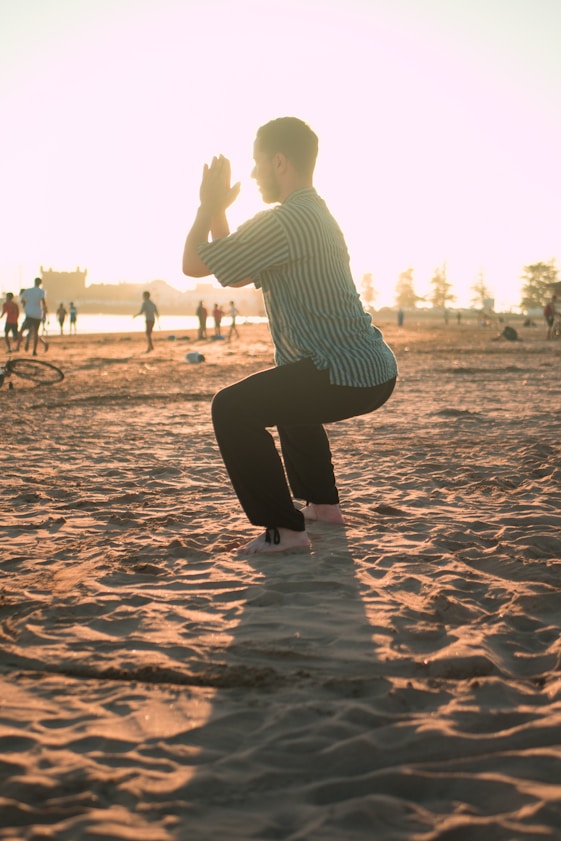 A man closing his hands white squatting on sand