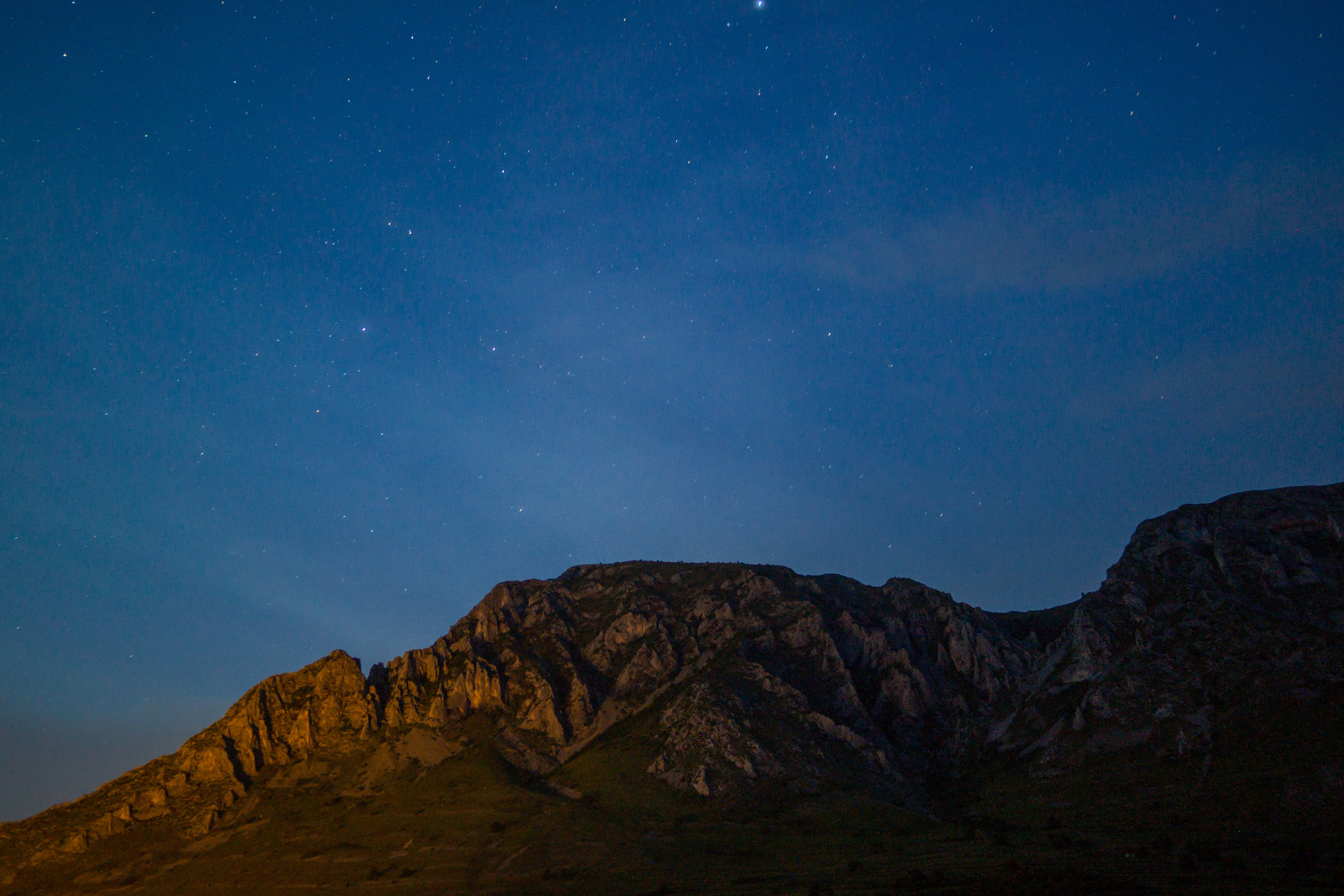 This photo is a 30 second exposure. It was taken at night, under completely dark sky. The left side of the mountain is lit by the lights of the village of Torockó. The mountain is situated in Erdély. I took this picture on my holiday as one of my first astrophoto attempts. Torockó is a beautiful Hungarian village and the locals are very kind and welcoming.