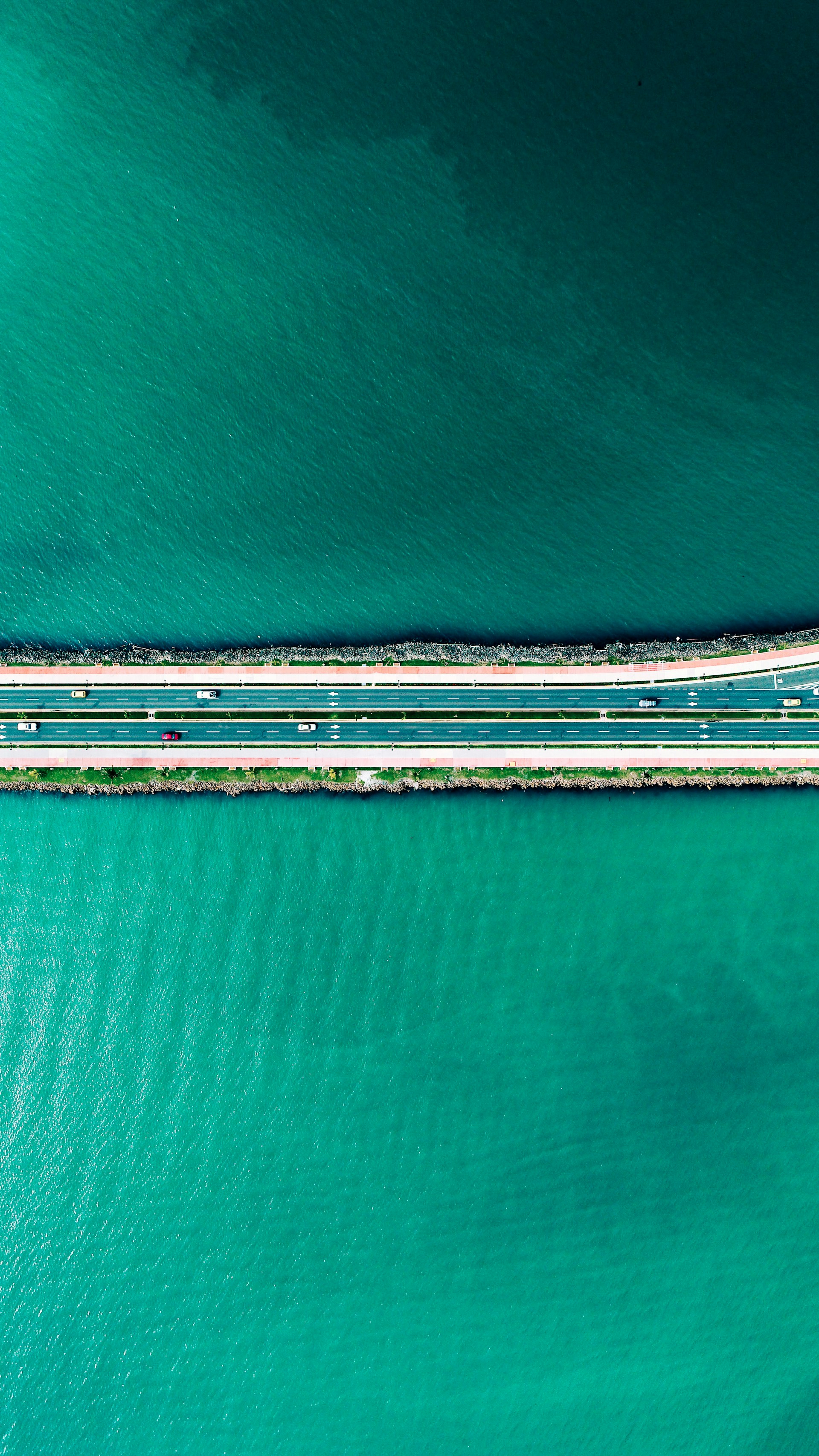 aerial photography of road between body of water