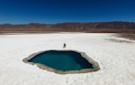 person wearing black shirt sitting near blue hole under blue sky during daytime