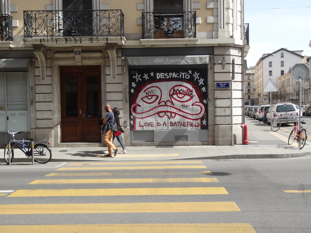 two people walking beside road beside upright building during daytime