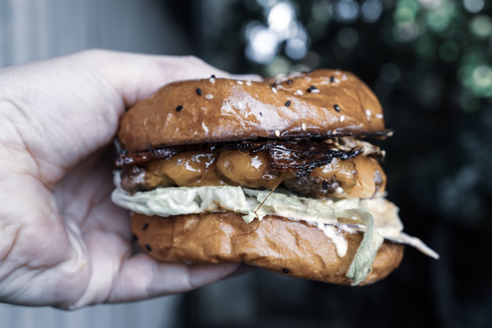 personne tenant un hamburger avec de la viande