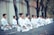 A group of taekwondo students in white uniforms bowing respectfully before training.