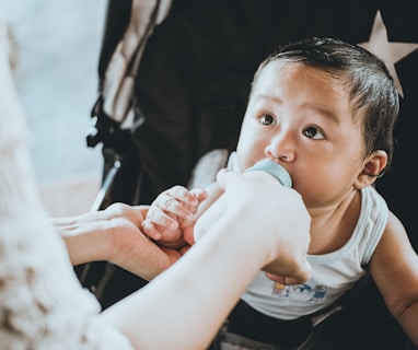 person feeding baby from feeding bottle