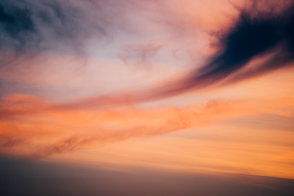 a plane flying in the sky at sunset