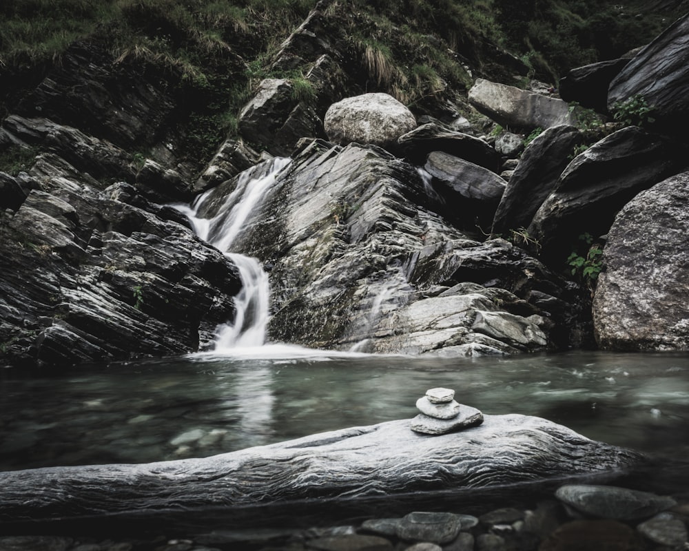 three piled stones near waterfall at daytime