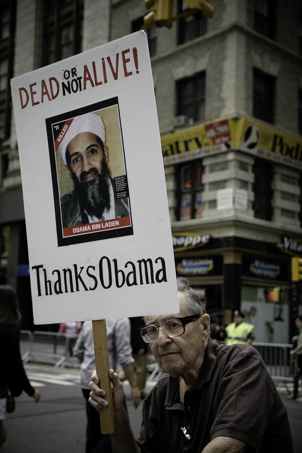 homme assis tenant Dead Not Alive ! Merci à la pancarte d’Obama