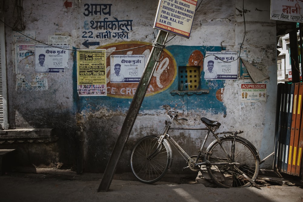 gray steel bicycle leaning on gray wall