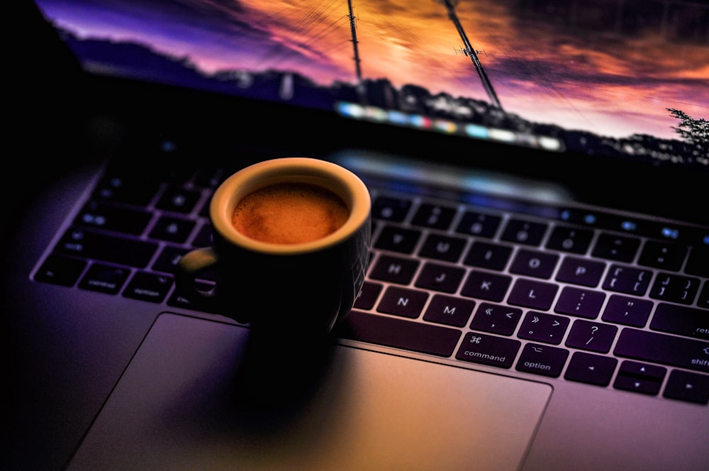 black ceramic coffee mug on MacBook Pro