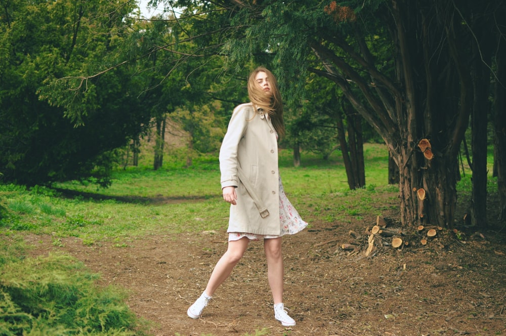 woman wearing gray coat standing near trees