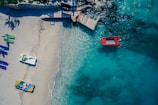 red boat on body of water near brown wooden foot board