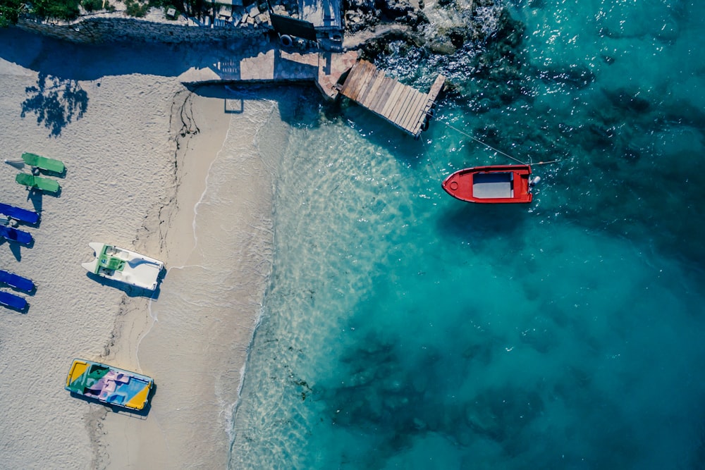 barco vermelho no corpo da água perto da tábua de madeira marrom