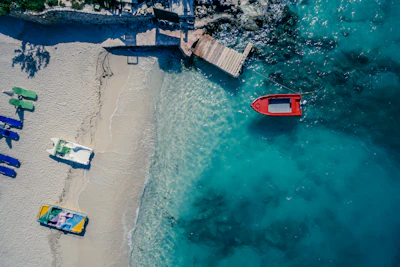 A red boat over the turquoise shallows at Ksamil, seen from above