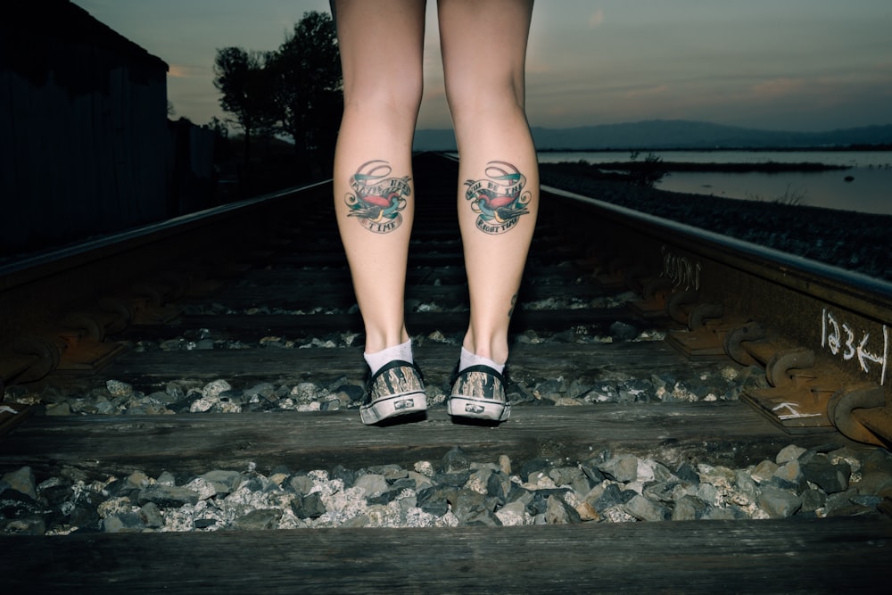 personne debout sur le chemin de fer avec tatouage de pied