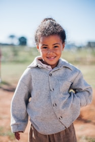 girl wearing grey button-up jacket while smiling
