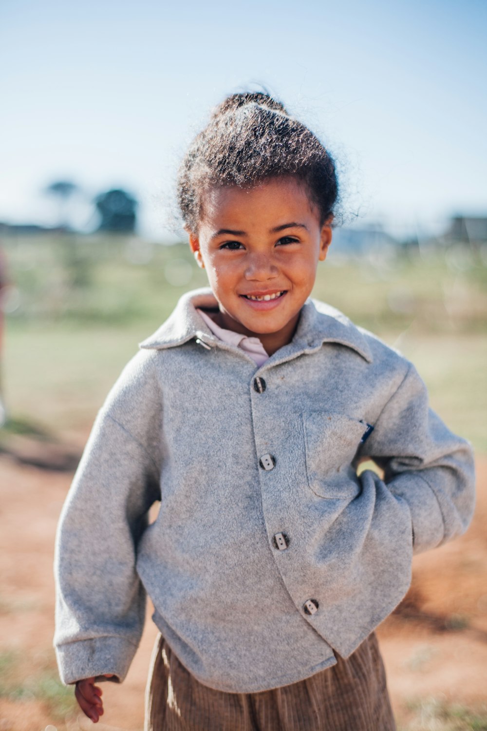 girl wearing grey button-up jacket while smiling