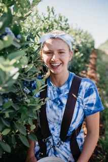 selective focus photography of woman standing beside green leafed plant