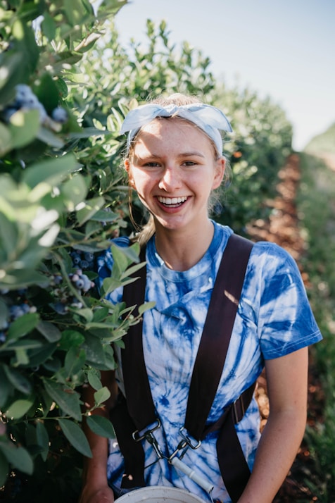 selective focus photography of woman standing beside green leafed plant