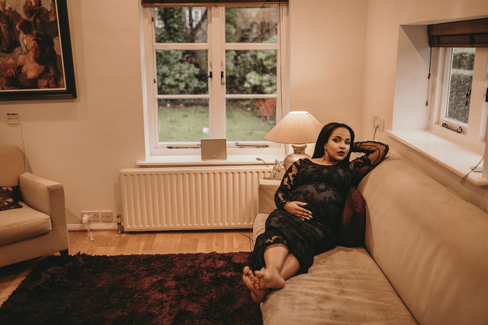 woman sitting on brown sofa near white radiator panel under glass window