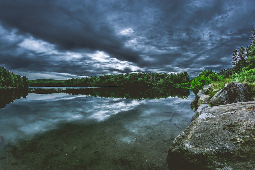 Cuerpo de agua rodeado de árboles bajo cielo nublado