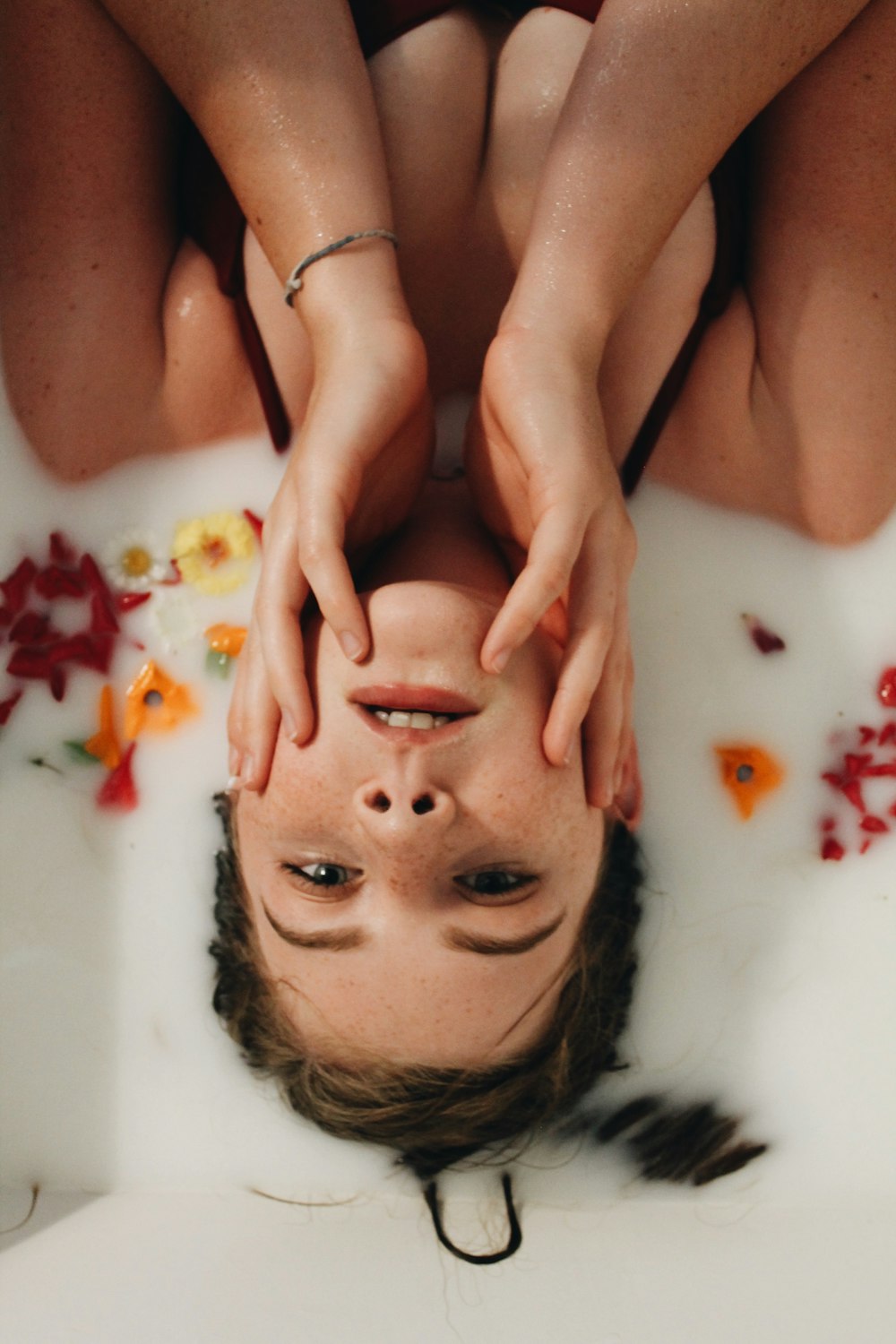 a woman laying in a bathtub with her hands on her head