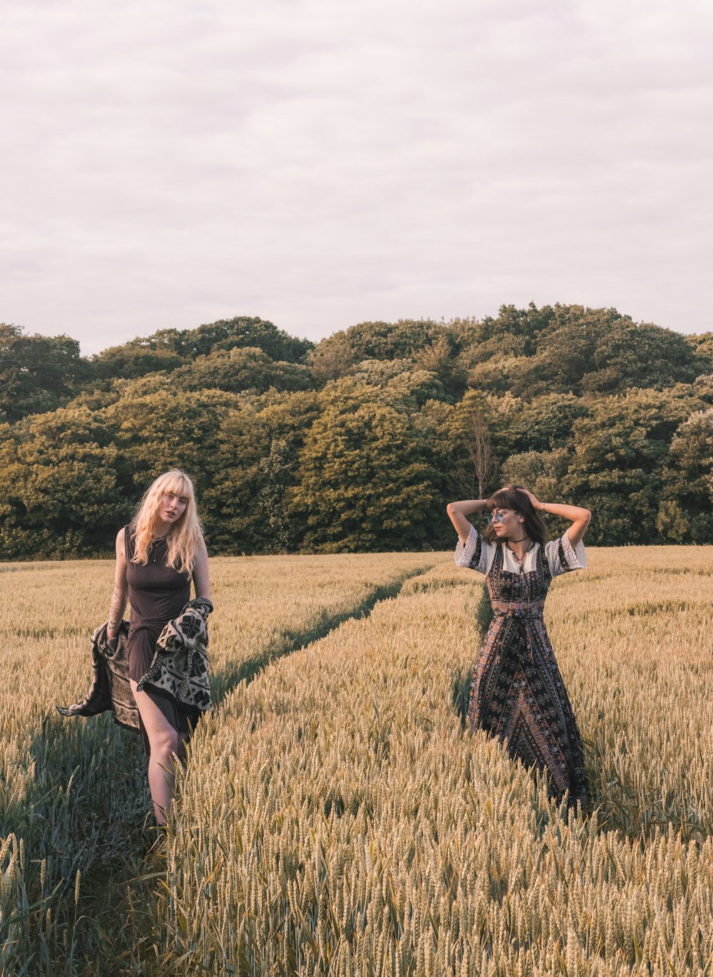two women walking on wheat field during daytime