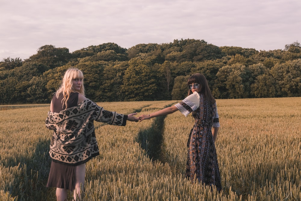 two woman walking while holding hands taking selfie