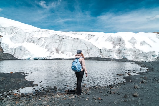 person standing on body of water near snowy mountain in Pastoruri Glacier Peru