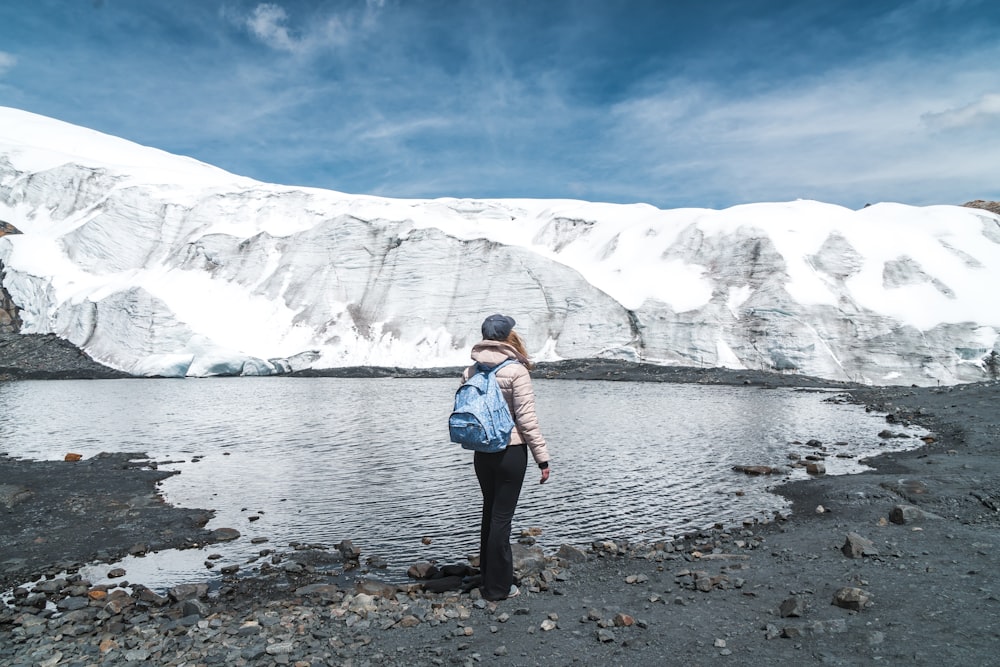 person standing on body of water near snowy mountain