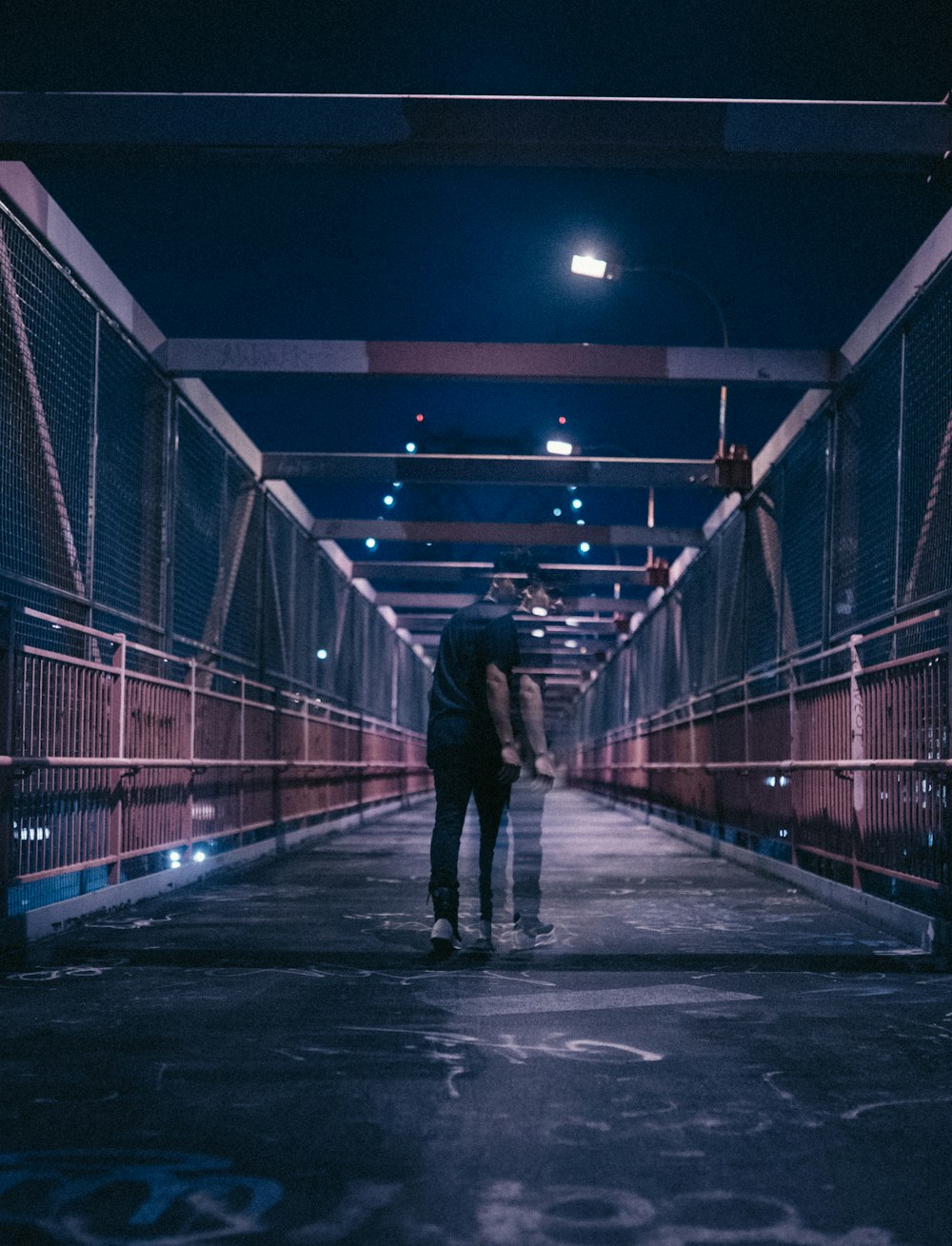 Mann geht nachts auf Brücke