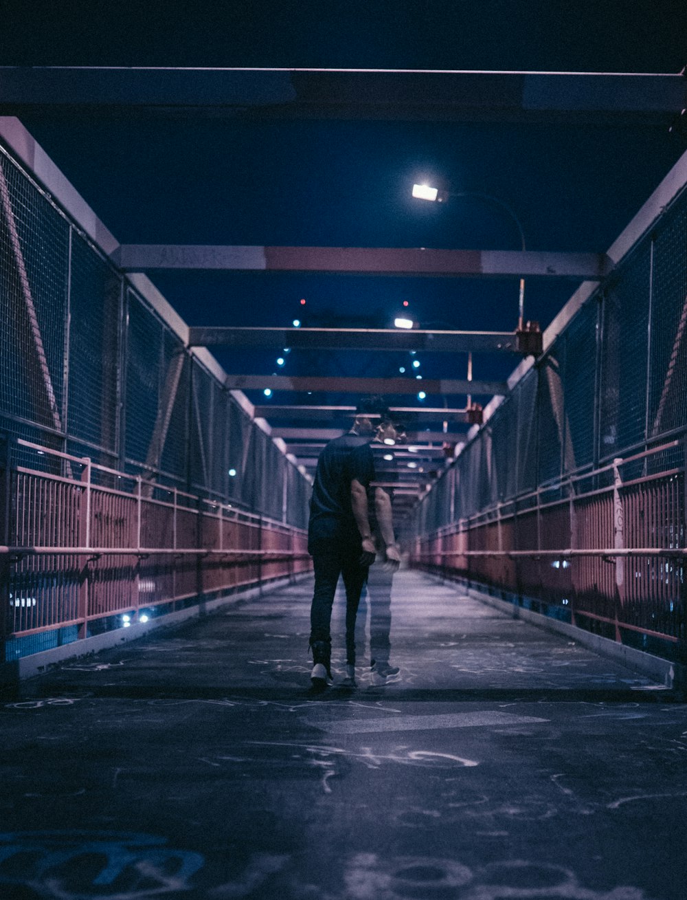 man walking on bridge during nighttime